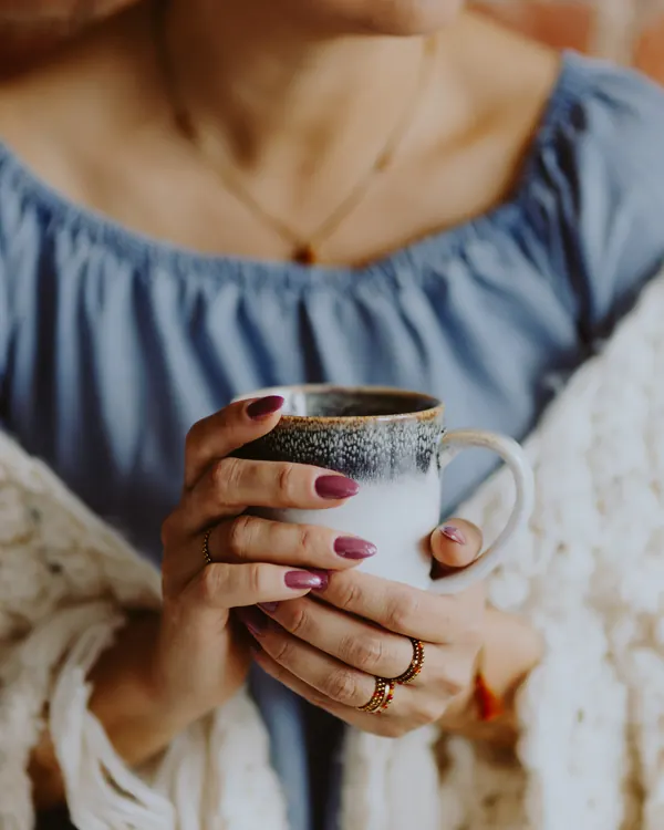 Mâini care țin o cană de cafea